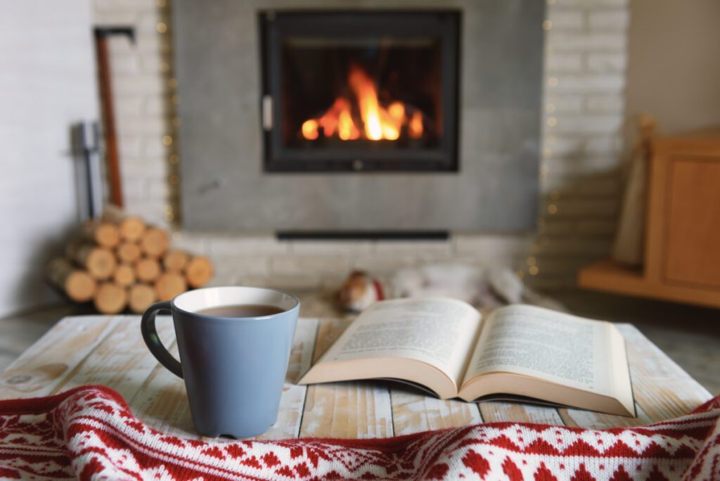 hyggowanie przy kominku z książką i ciepłą herbatą