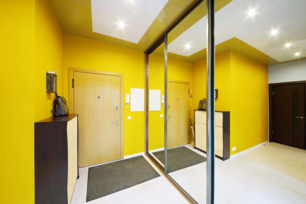 jasny przedpokój z żółtymi ścianami i dużym lustrem