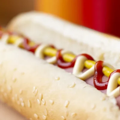 zbliżenie na hot doga z parówką i trzema różnymi sosami ketchupem majonezem i musztardą