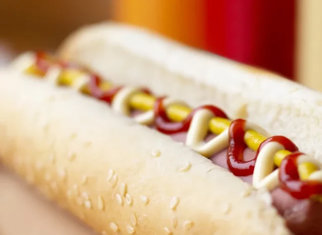 zbliżenie na hot doga z parówką i trzema różnymi sosami ketchupem majonezem i musztardą