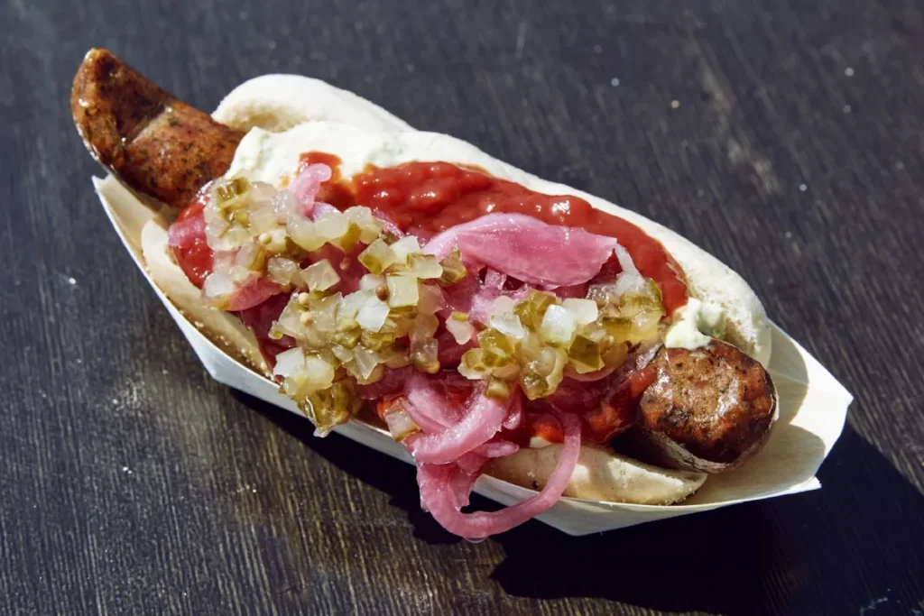 hot dog na stole z kiełbaską ketchupem i cebulką