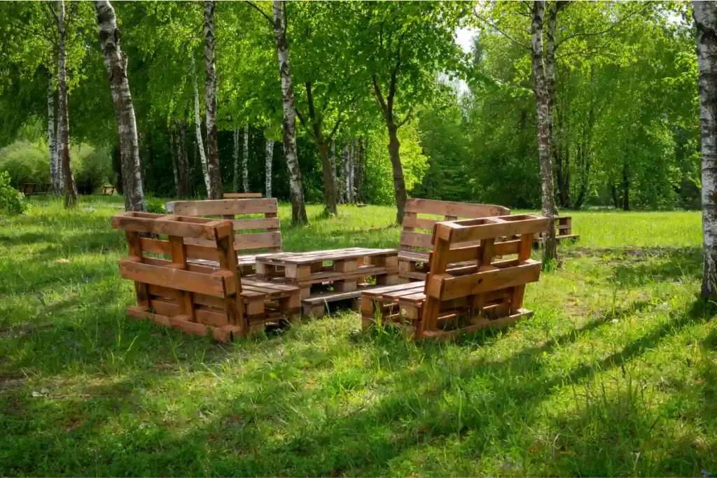 meble ławki i stolik z palet w ogrodzie na tle lasu i zieleni