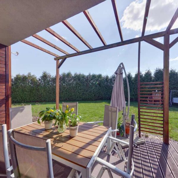 Taras drewniany z zadaszeniem i stołem ogrodowym w ogrodzie