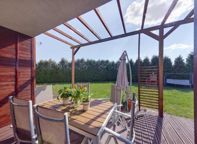 Taras drewniany z zadaszeniem i stołem ogrodowym w ogrodzie