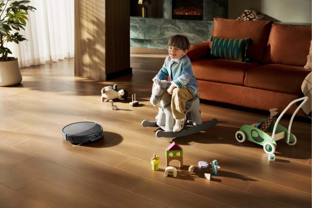 Robot sprzątający Roborock Saros 20 poruszający się po podłodze w salonie z zabawkami dziecka