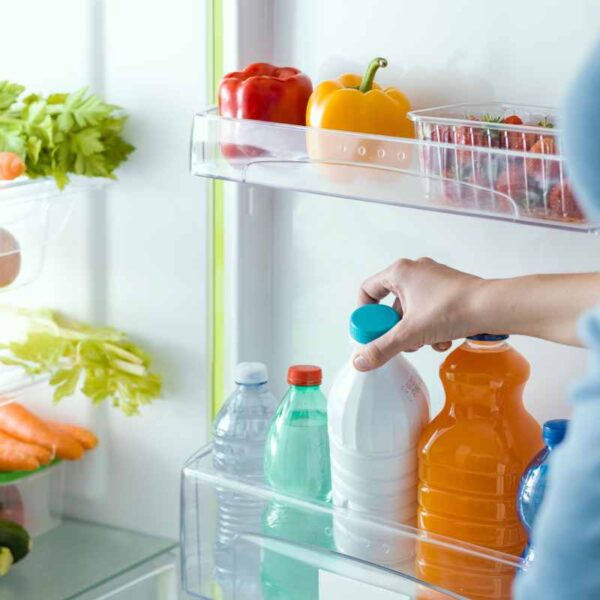 ręka wkładająca napoje do półki w lodówce
