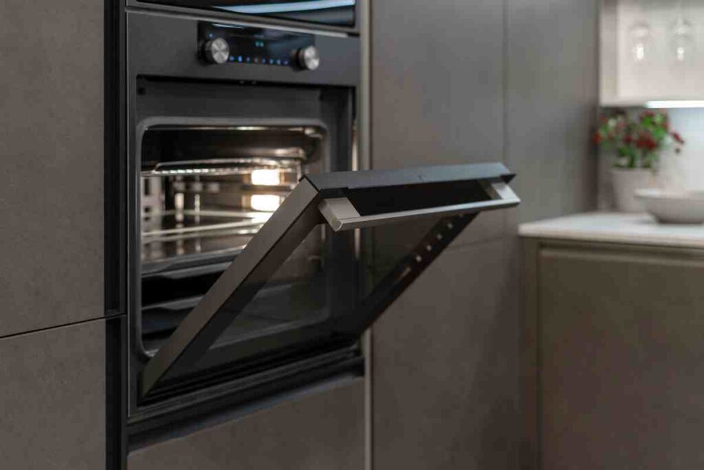 Piekarnik dual cook do zabudowy z uchylonymi drzwiczkami w nowoczesnej kuchni