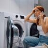Kobieta szukająca pomocy z powodu awarii pralki w domowej łazience