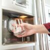 Szklanka z kostkami lodu podstawiona pod dozownik lodówki z kostkarką