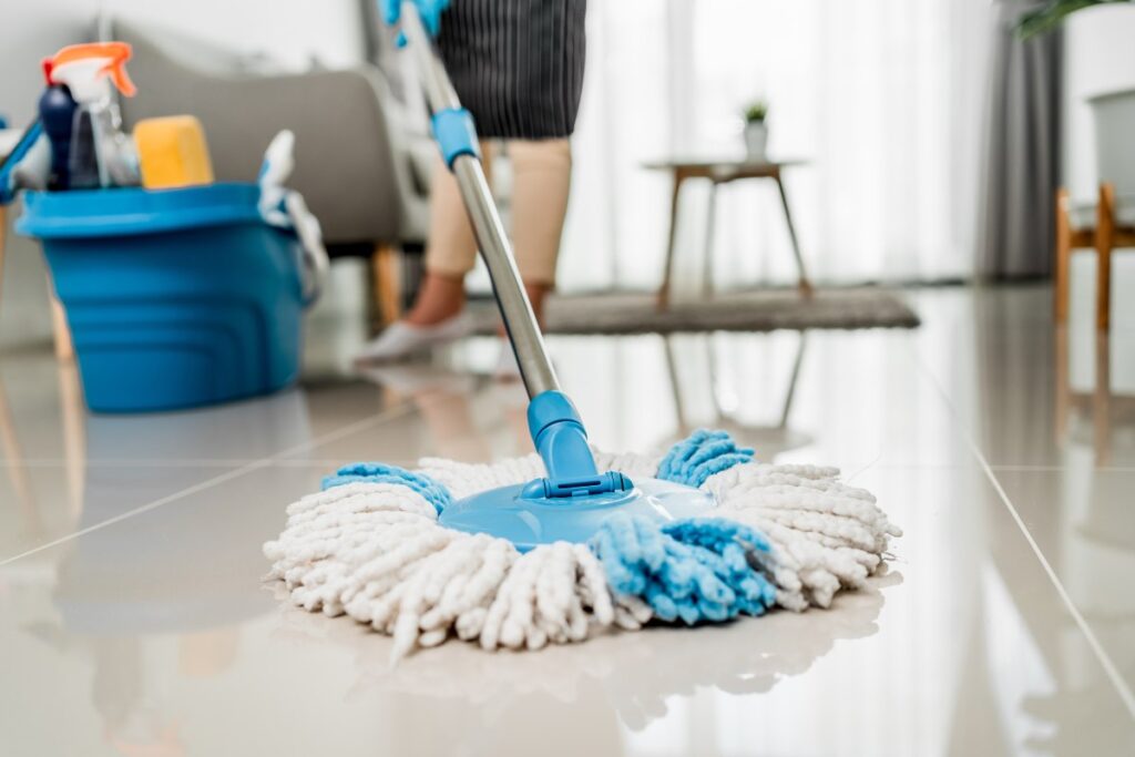 Mop obrotowy z nakładką z mikrofibry podczas mycia podłogi z płytek w salonie