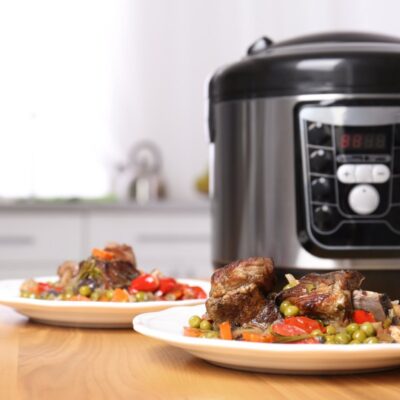 Multicooker na blacie kuchennym obok talerzy z gotowym daniem
