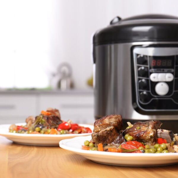 Multicooker na blacie kuchennym obok talerzy z gotowym daniem