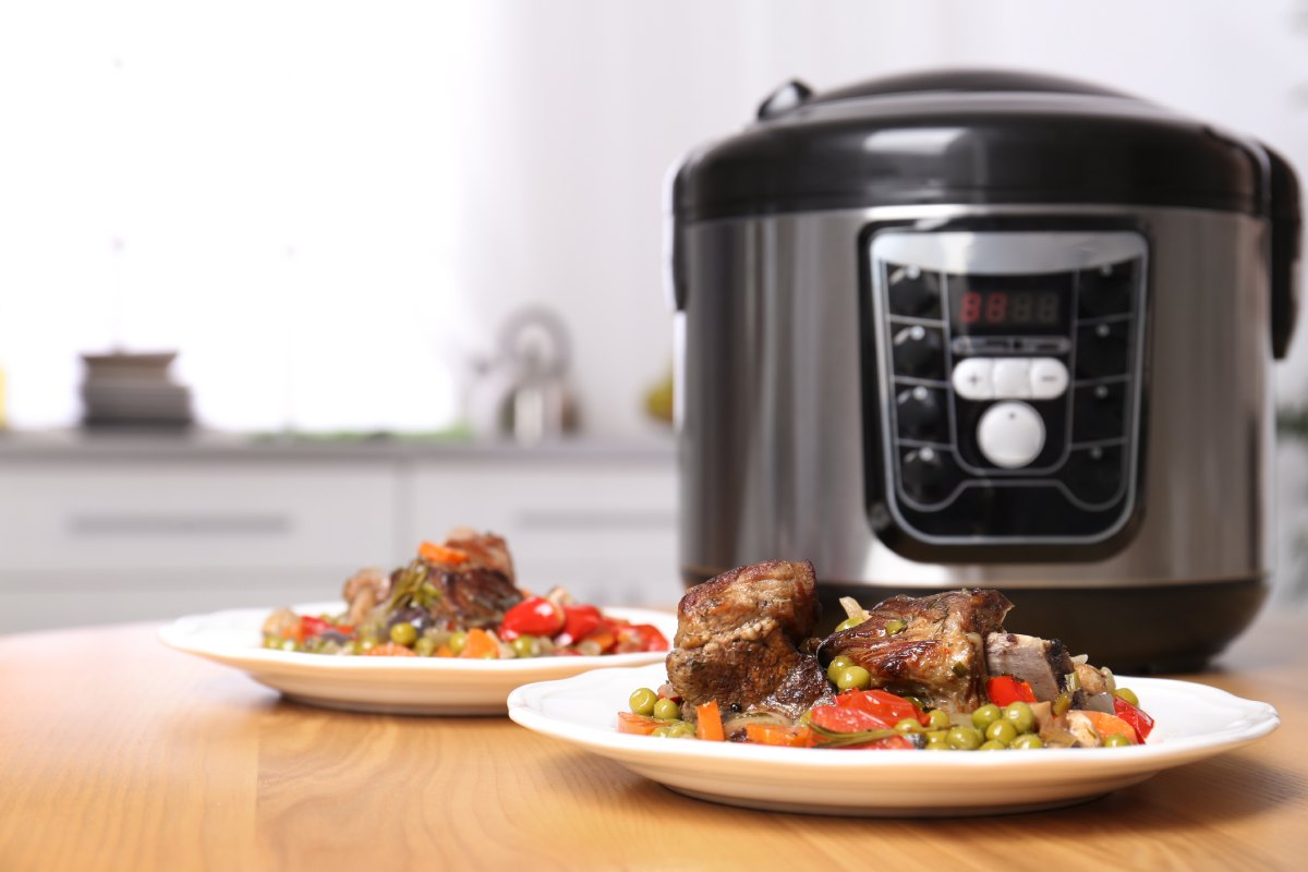 Multicooker na blacie kuchennym obok talerzy z gotowym daniem